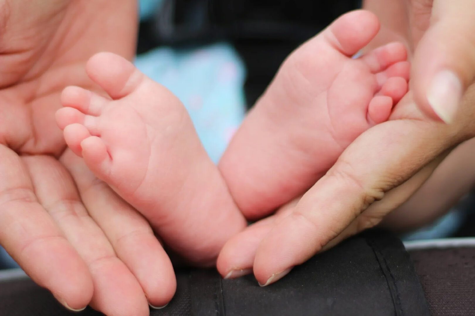 Newborn baby feet in caring hands